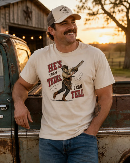 Man wearing He's From Texas beige graphic tee with vintage chainsaw icon design