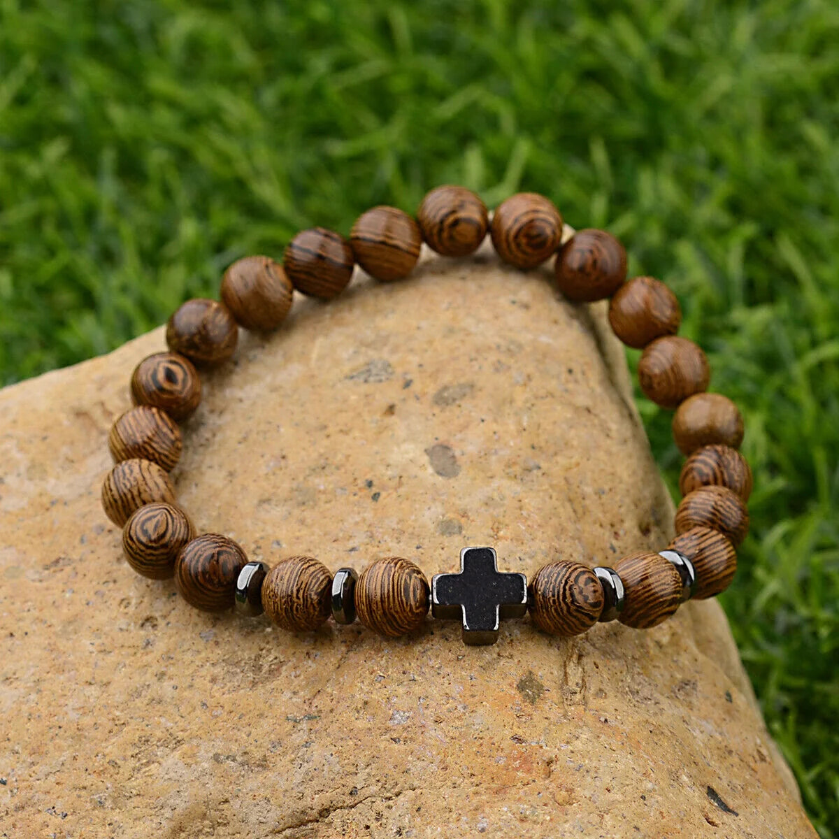 Christian cross bracelet outdoors on stone with grass