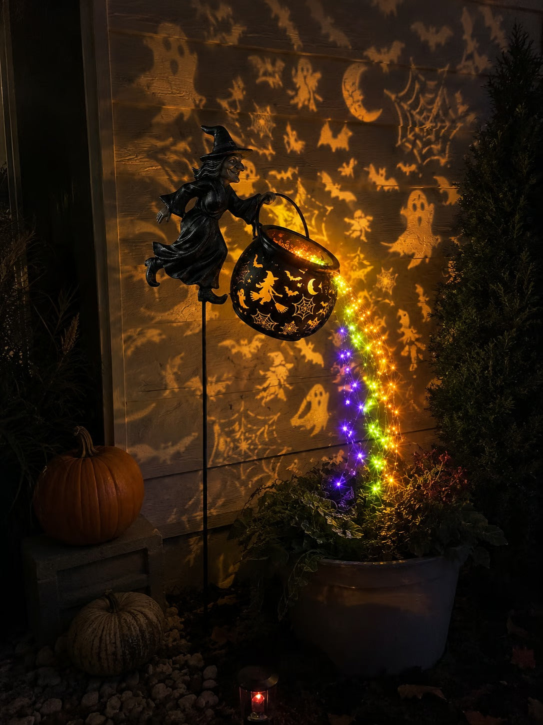 Halloween witch cauldron light beside outdoor flower planter