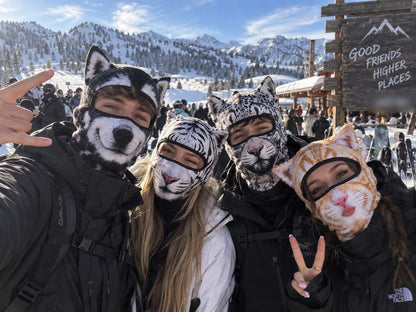 Friends wearing animal print ski balaclavas for a snowy mountain group photo