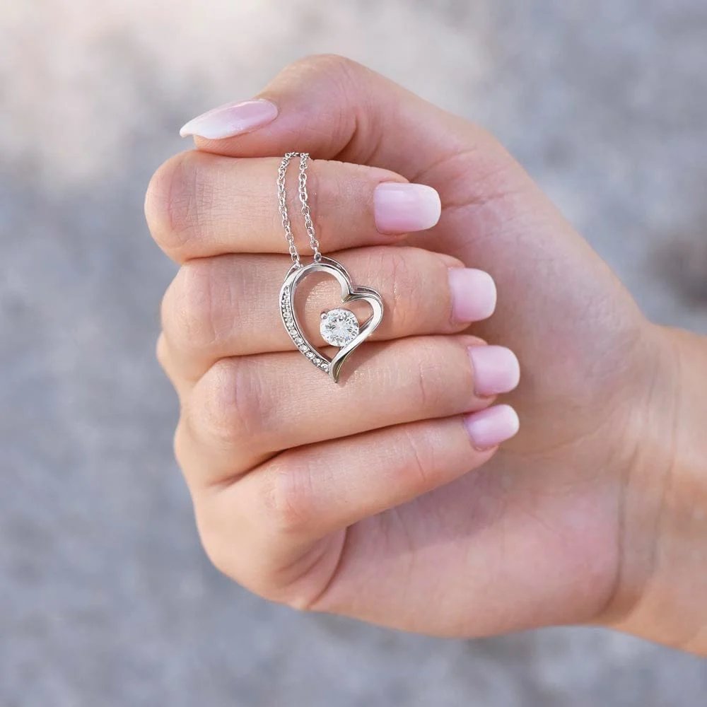 White gold finish daughter heart necklace held in a hand to show pendant detail
