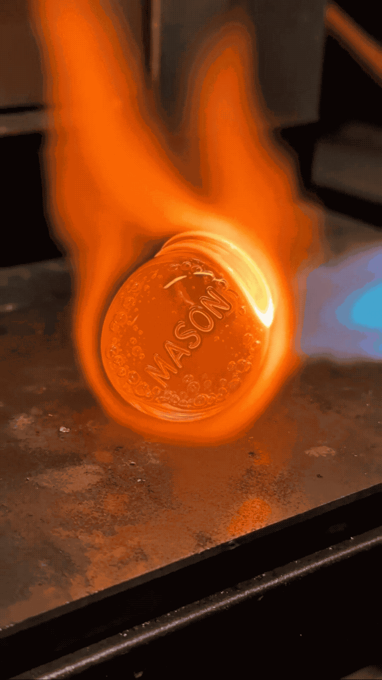 Recycled mason jar glass being hand-shaped over open flame into a turtle