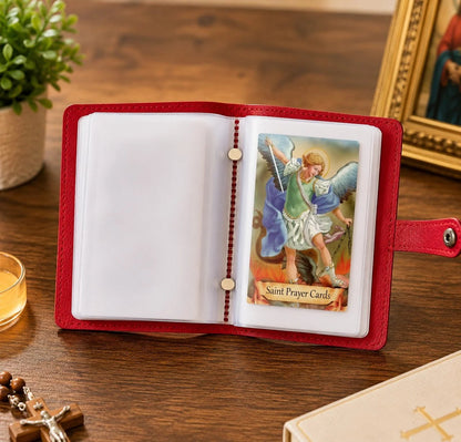 Red genuine leather holy card holder open with saint prayer cards on wooden table