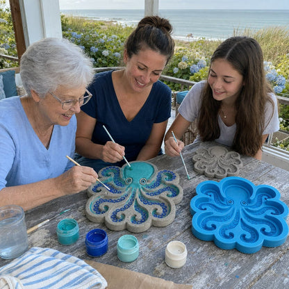 Family painting octopus stepping stones in coastal garden