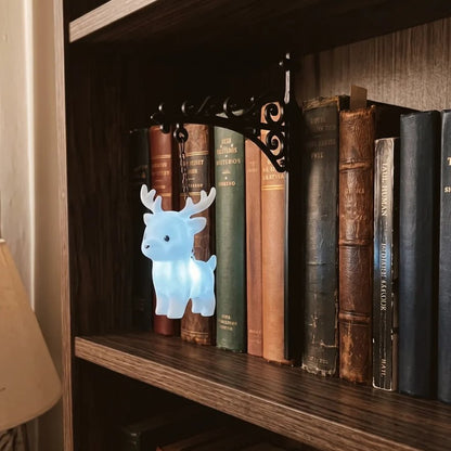 Stag figurine night light glowing blue on bookshelf