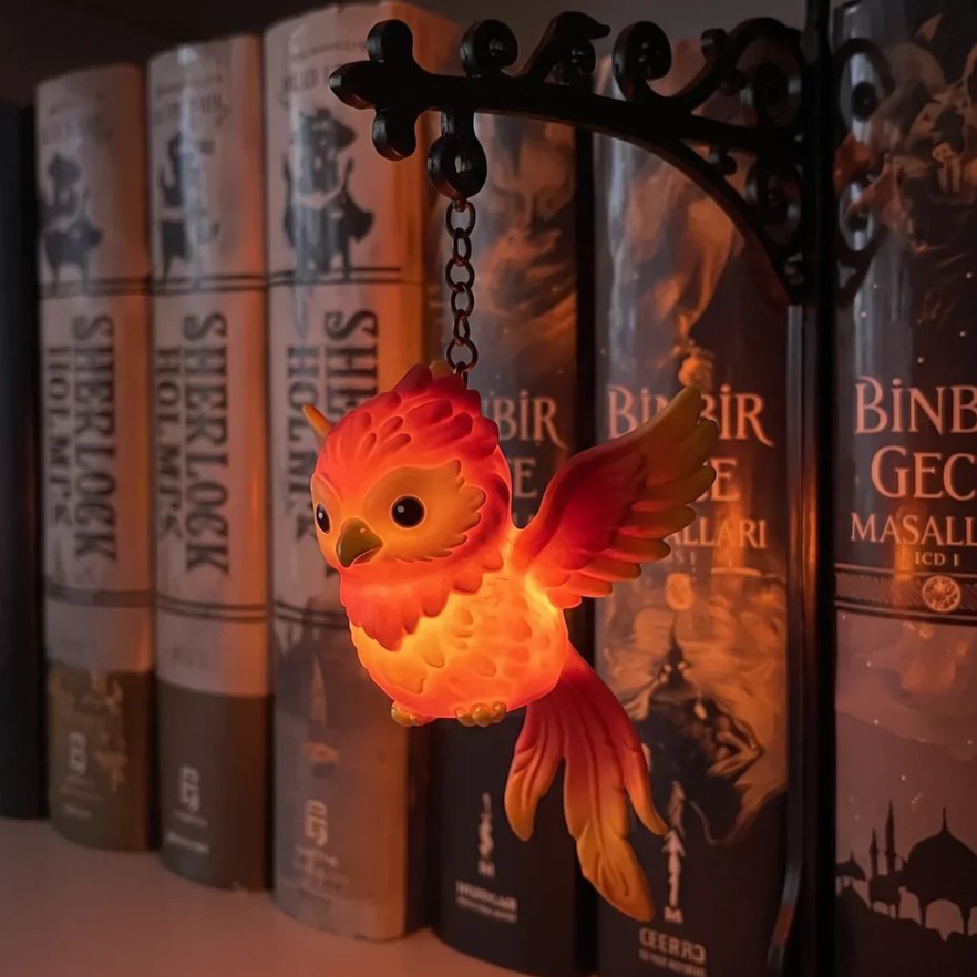 Phoenix figurine night light glowing red on bookshelf