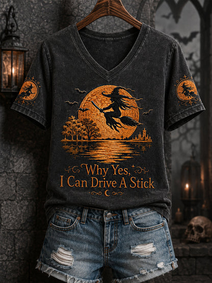 Women's black V-neck Halloween tee with orange witch-on-broom print and 'Why Yes I Can Drive A Stick' text